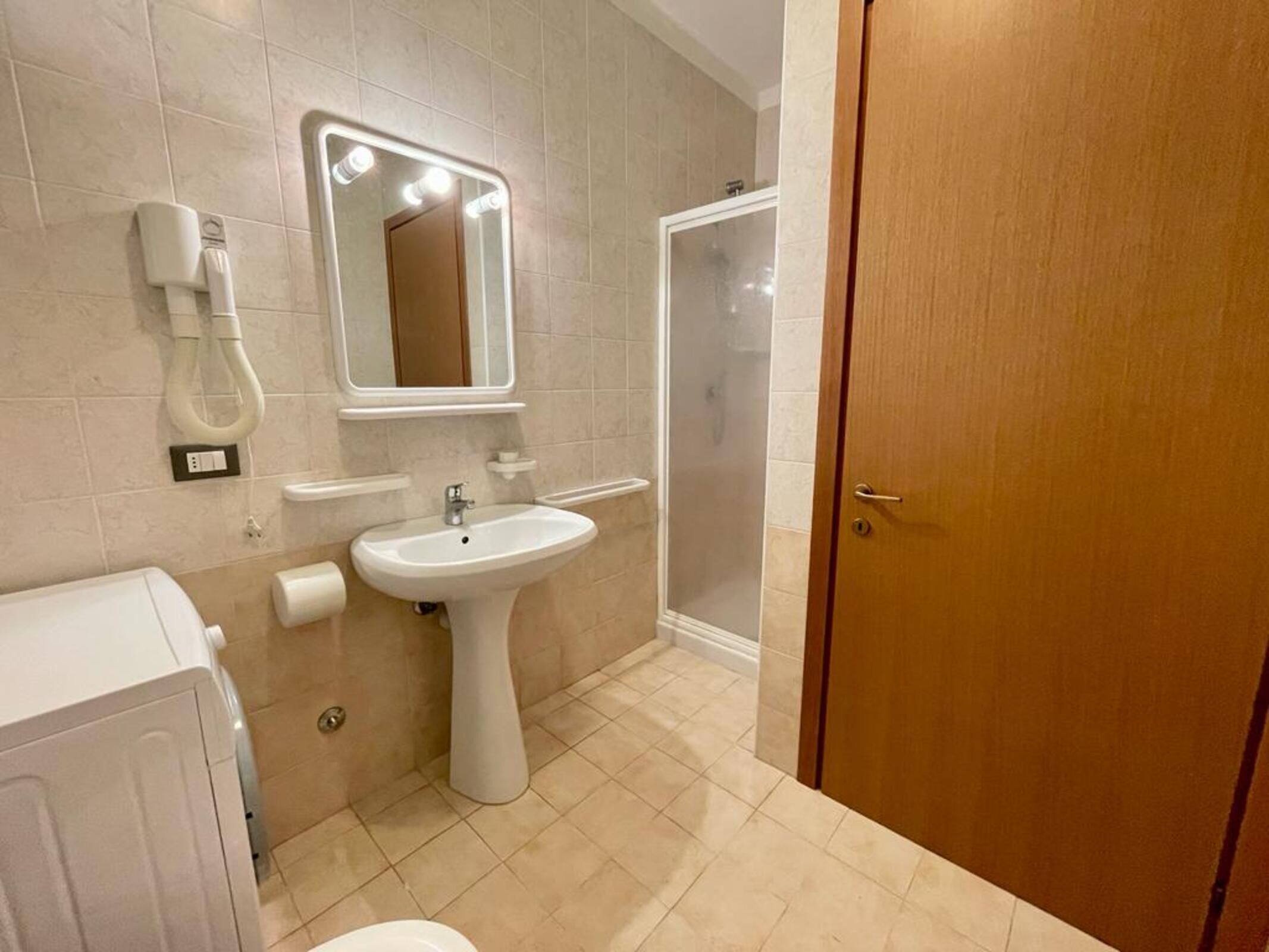 A bathroom with a sink, mirror, and shower.