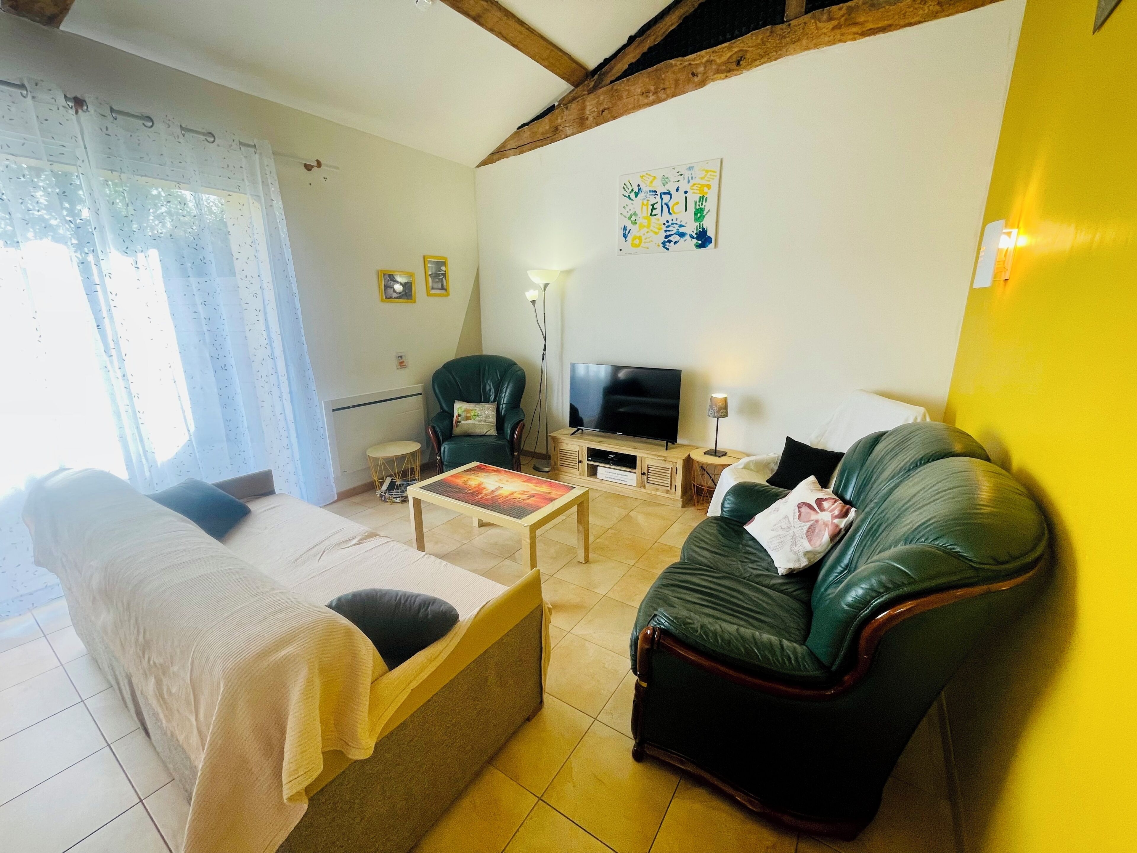 Un salon avec un canapé, un téléviseur, une lampe et un tableau accroché au mur.