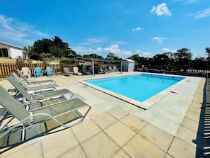 A swimming pool with lounge chairs and a small shed.