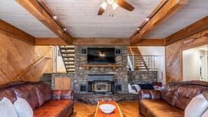 A cozy living room with a stone fireplace, leather sofas, and a wooden coffee table.