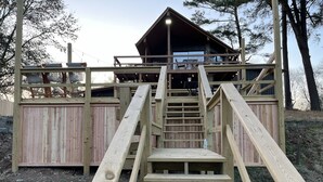A wooden deck with a staircase leading to a covered area with a table and chairs.