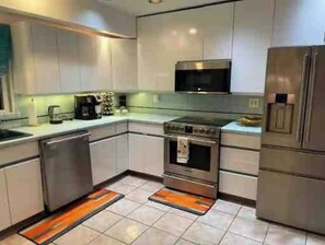 A modern kitchen with stainless steel appliances, white cabinets, and a microwave above the stove. - Comfort Haven/King-Sized Bed/Near Nautical Mile- 20 minutes from JFK (Baldwin)