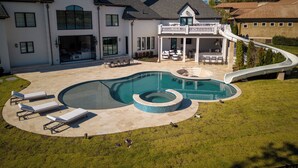 Una casa grande con piscina, un porche techado y un tobogán.