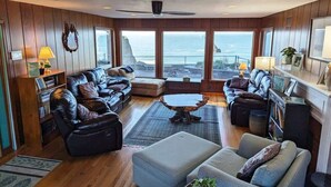 A spacious living room with leather sofas, a central coffee table, and large windows offering a view of the ocean. - Sparkling Clean, Private & Quiet! Amazing Ocean Views [3] (Brookings)