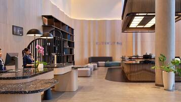 A hotel lobby with a reception desk, a bar area, and a seating space.