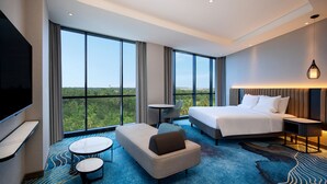 Quarto de hotel com uma cama grande, um sofá, uma mesinha e uma televisão.