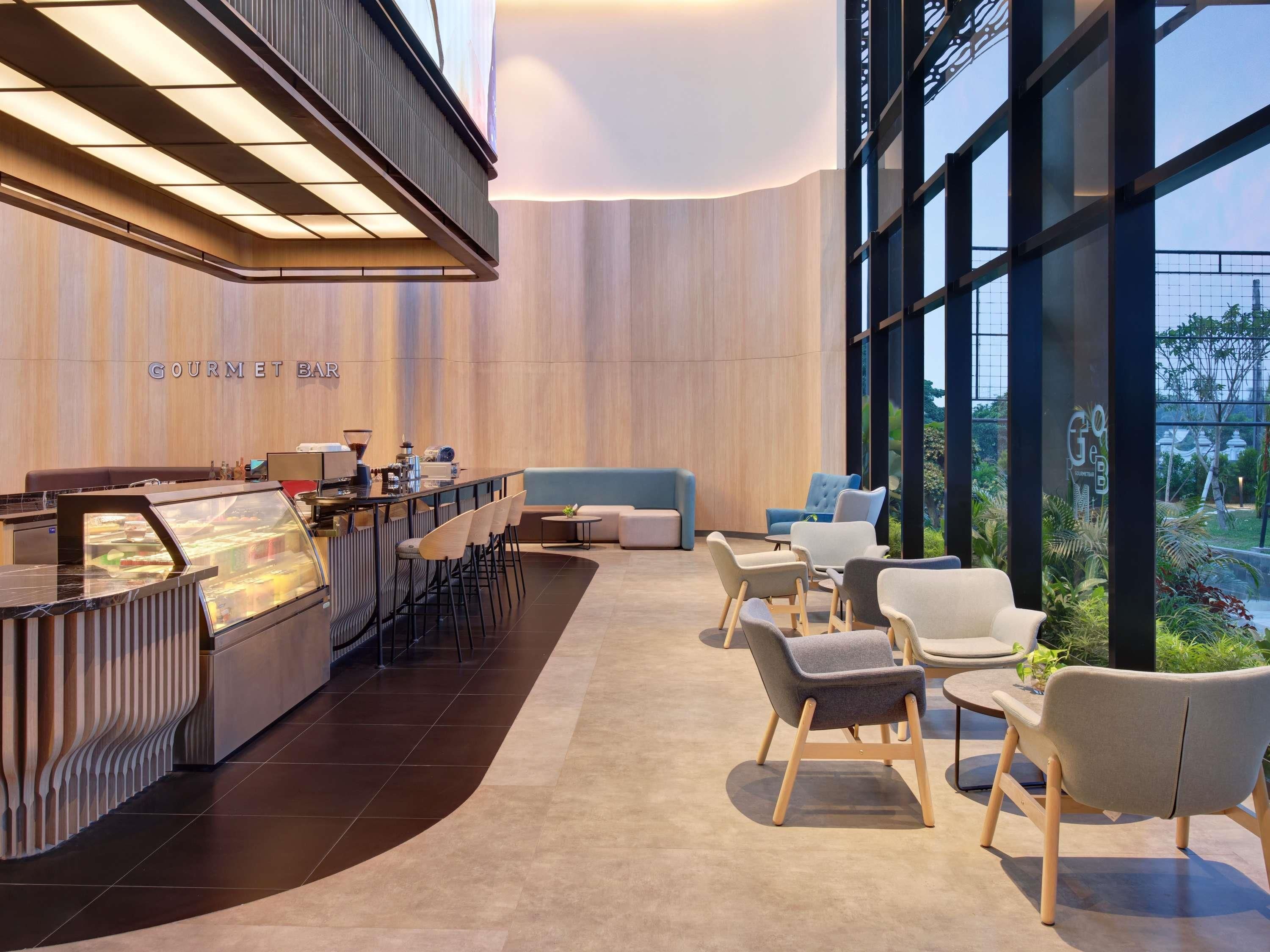 A modern bar area with a counter, seating, and a view of greenery outside.