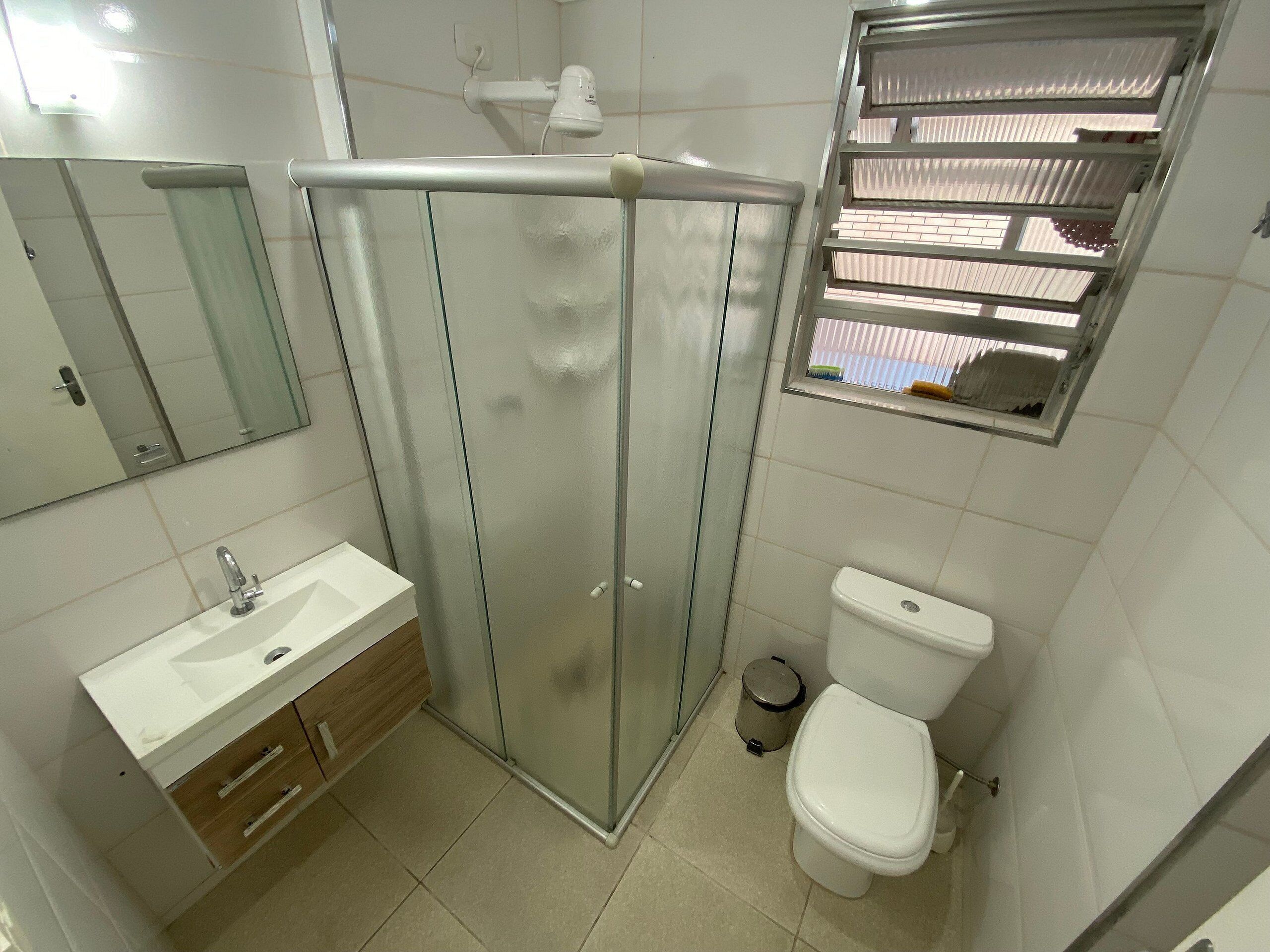 A modern bathroom with a glass shower enclosure, a white sink, and a toilet.