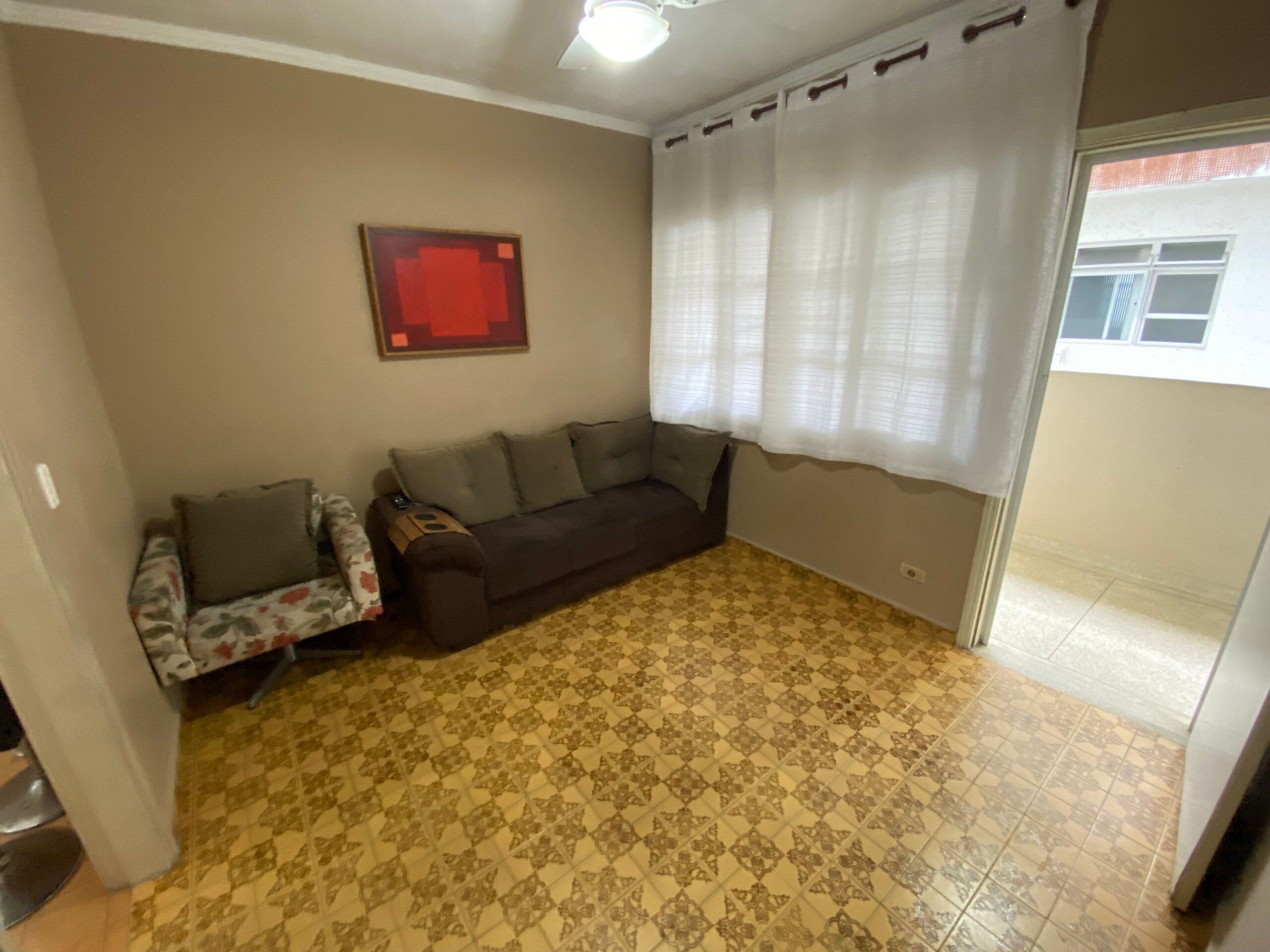 A living room with a patterned floor, a sofa, a chair, and a window with curtains.
