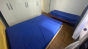 A room with a large bed, a smaller bed, and a wardrobe with two doors. - Foot in the sand Corner of Fort II - Tiradentes 3 (Praia Grande)