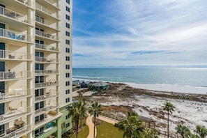 A high-rise hotel with multiple balconies overlooking a beach.