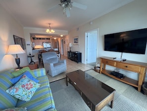 A living room with a sofa, coffee table, TV, and a ceiling fan.