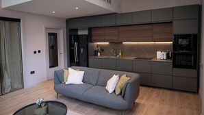 A modern kitchen with built-in appliances, a grey sofa, and a glass coffee table. - Luxury Stunning 2bed Apt City Centre (Manchester)