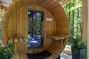 A circular wooden structure with a glass door, a bench, and a small table.