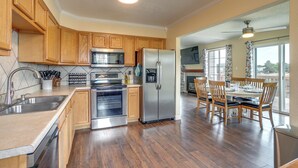 A modern kitchen with wooden cabinets, stainless steel appliances, and a dining area with wooden chairs and a table.