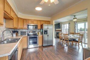 A modern kitchen with wooden cabinets, stainless steel appliances, and a dining area with wooden chairs and a table.