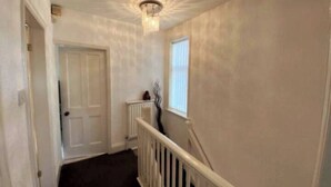 A hallway with a white door, a radiator, and a window with blinds. - Budgeted Shared Residence near Coventry Building Society (CBS) Ricoh Arena & M6 (Coventry)