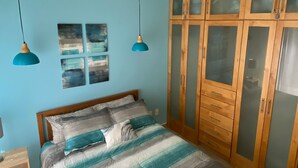 A bedroom with a bed, wooden wardrobe, ceiling fan, and two pendant lights. - Awesome Villa 2 Chic Pool & Hot Tub  (El Sargento)