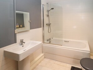 Une salle de bain avec un lavabo blanc, une baignoire et une douche à parois de verre.