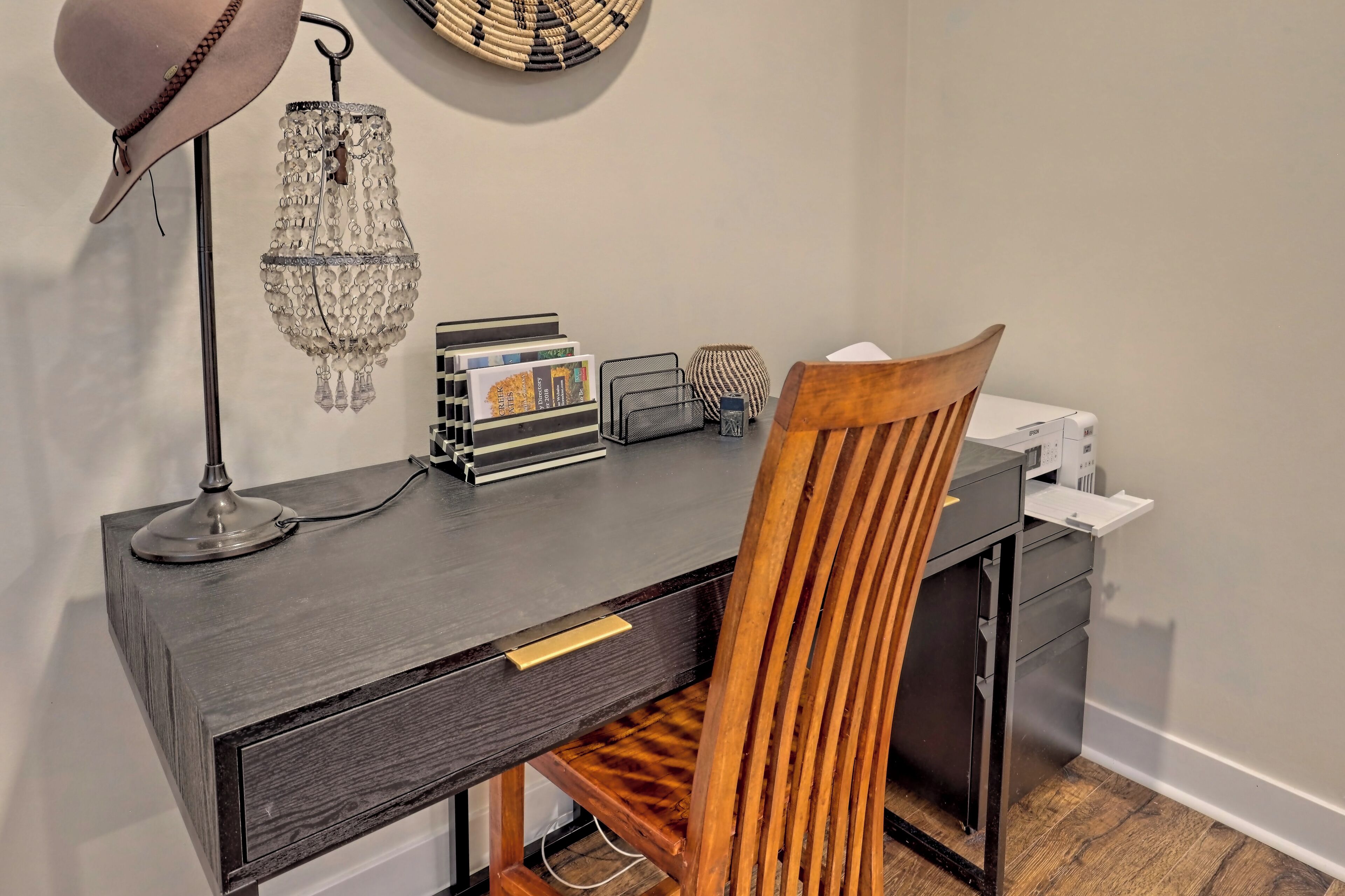 A desk with a lamp, a crystal chandelier, and a wooden chair.