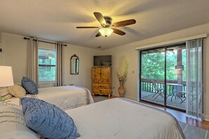 Une chambre avec deux lits, un ventilateur de plafond, une commode et une grande fenêtre donnant sur l’extérieur.