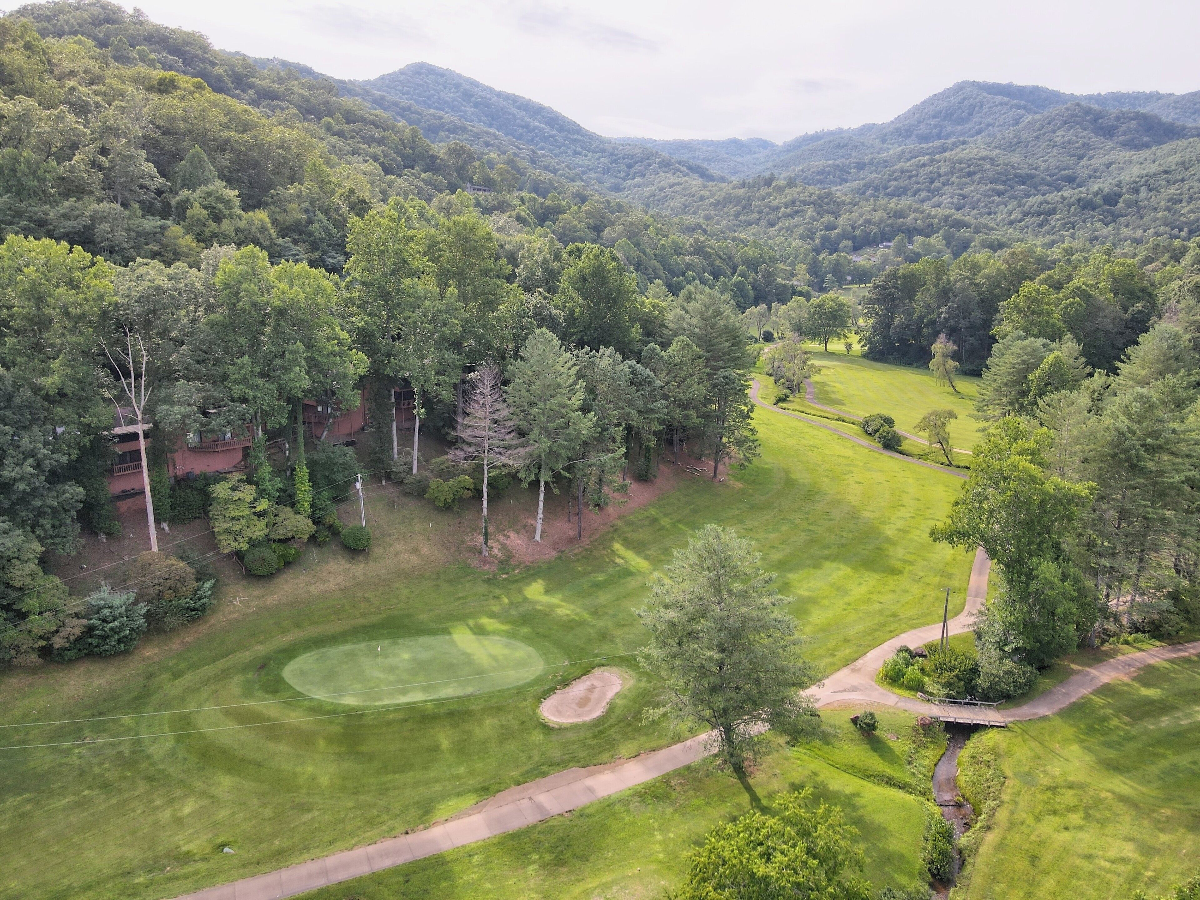 An aerial view of a golf course with a well-maintained fairway, sand bunkers, and a water hazard.