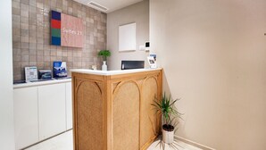 Un espace d’accueil comprenant un comptoir de réception, un panneau indiquant « Suites 21 », une plante et un luminaire fixé au mur.