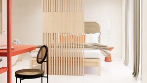 Habitación de hotel moderna con cama, escritorio, silla y separador con listones verticales.