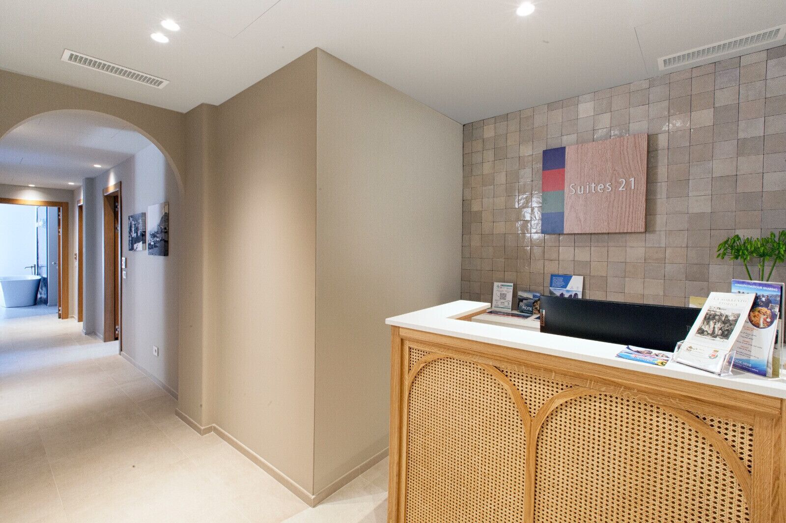 Een receptie met een receptiebalie, een prikbord en een gang naar een badkamer.
