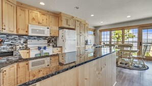 Een keuken met houten kastjes, een marmeren aanrechtblad en uitzicht op het omliggende landschap.