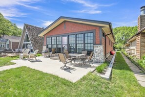 A modern building with a patio area, outdoor seating, and a stone accent wall. - Anchors Away Cottage on Big Spirit Lake (Lakefront) (Orleans)