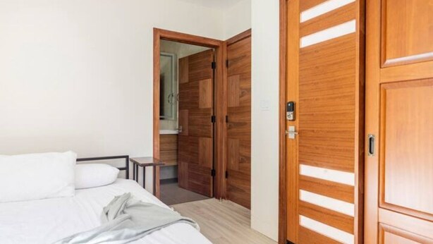 Un dormitorio con cama, un armario de madera y una mesita.