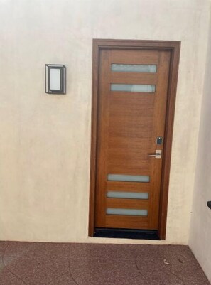 Stylish door with horizontal slats and a glass panel, set in a plain wall.