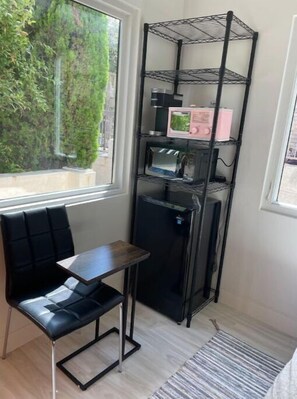 Cozy retreat with a functional layout, featuring a storage unit, small table, and comfortable bench.