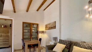 Un salón acogedor con una mesa de comedor de madera, un sofá con cojines estampados y una estantería.