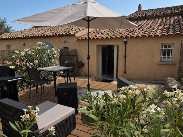 A patio with outdoor furniture, a covered seating area, and a building with a tiled roof.