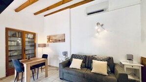 Una sala de estar acogedora con un sofá, una mesa de comedor con sillas, una estantería y un cuadro en la pared.