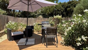 Un patio al aire libre con una parrilla, asientos y un paraguas grande.
