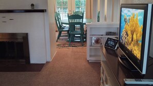 En stue med tv, pejs og spiseplads med stole og bord.