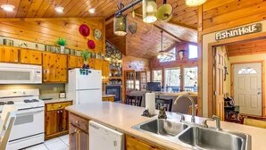 A kitchen with wooden cabinets, a white refrigerator, a stove, and a dishwasher. - Katahdin Cabin Rustic Romance + Indoor Hot Tub Near Town (Blue Ridge)
