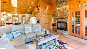 A cozy cabin interior with a fireplace, wooden walls, and a dining area. - Katahdin Cabin Rustic Romance + Indoor Hot Tub Near Town (Blue Ridge)