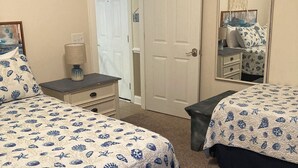 Un dormitorio con dos camas, una mesita de noche, un tocador y una puerta.