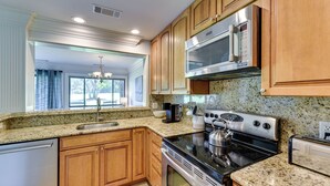 A modern kitchen with granite countertops, stainless steel appliances, wooden cabinets, and a dishwasher. - Palmetto Dunes Golf Getaway: Pool + Beach Access! (Hilton Head Island)