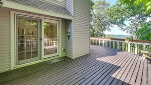 Eine Holzterrasse mit einer Schiebetür, die zu einer überdachten Patio führt.