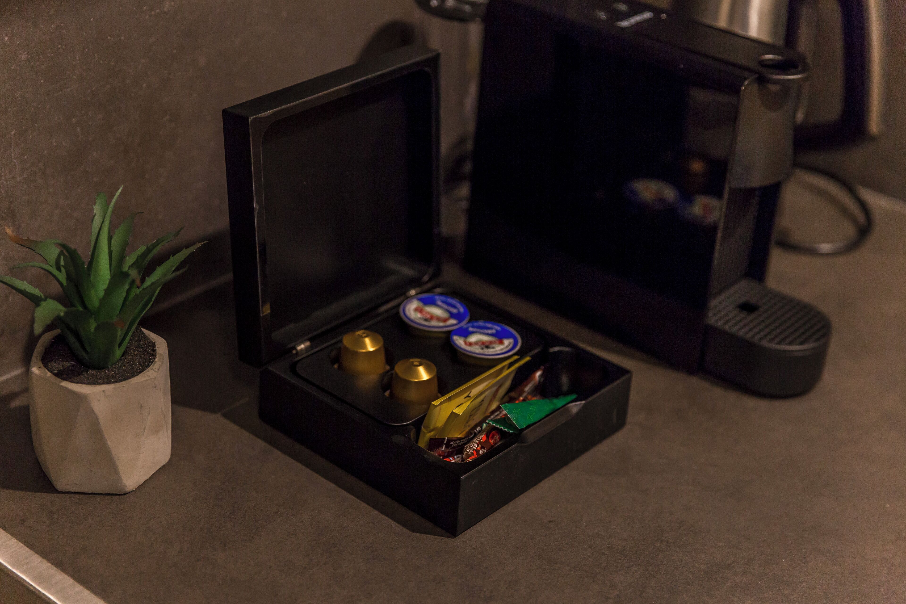 A small black box with a plant, a coffee machine, and some items inside.