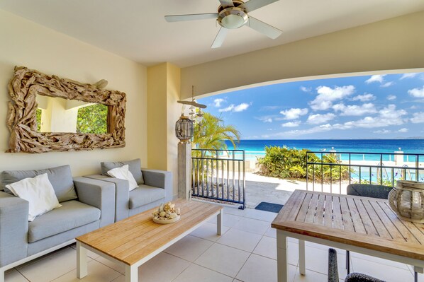 A balcony with a view of the ocean, a ceiling fan, and a rustic mirror.
