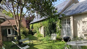 Ein Garten mit Rasenfläche, einer Bank, einem Tisch und einem Grill.