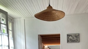 Ein Essbereich mit einem runden Tisch, schwarzen Stühlen, einer geflochtenen Pendelleuchte und einem Mülleimer.