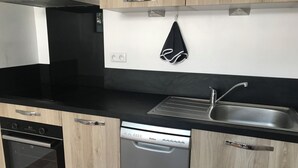 Eine moderne Küche mit schwarzen Arbeitsplatten, Edelstahlgeräten und Holzschränken.