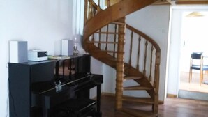 Ein Zimmer mit einer Holztreppe, einem Klavier und einer weißen Wand.